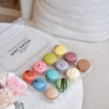 A box of 12 macarons, sitting on a table