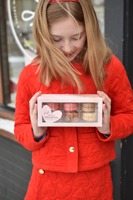 Girl holding box of 6 French macarons in custom Valentine box available in Grand Rapids, Ann Arbor and Holland Michigan.