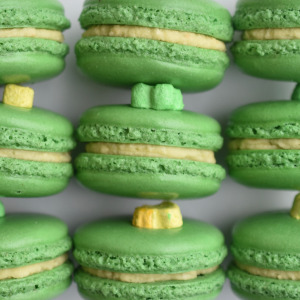 Lucky Charms French macaron featuring green macaron shells topped with a marshmallow and filled with Lucky Charm cereal buttercream.