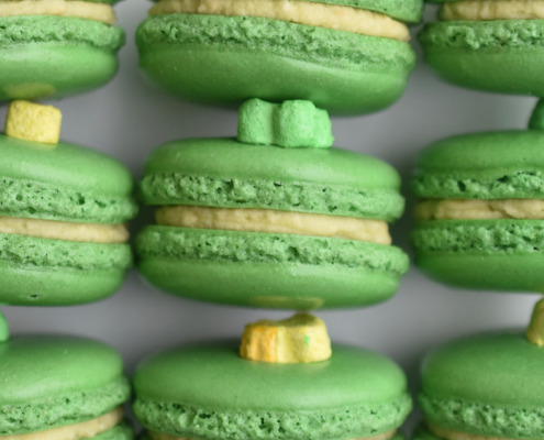 Lucky Charms French macaron featuring green macaron shells topped with a marshmallow and filled with Lucky Charm cereal buttercream.
