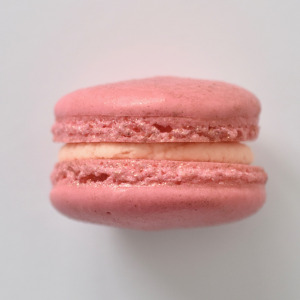 Rosé French macaron featuring pink macaron shells dusted in rose gold shimmer dust, filled with a rosé flavored buttercream.