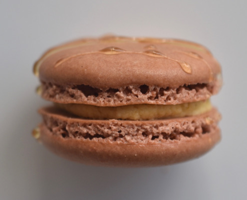 Stroopwafel French macaron featuring tran macaron shells topped with a caramel drizzle, filled with a stroopwafel buttercream.