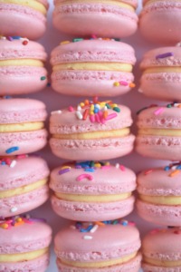 Sugar Cookie French Macarons Pink French macarons topped with rainbow sprinkles, filled with a sugar cookie buttercream.